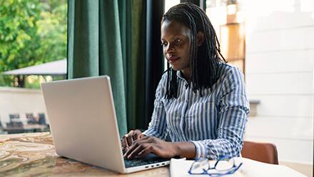 A woman sitting at a table on her laptop working toward her associate degree