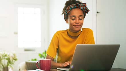 A person using a laptop, researching how long it takes to get her bachelor's degree online.