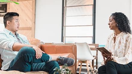 A female therapist and a male patient sitting across from one another during a sessions