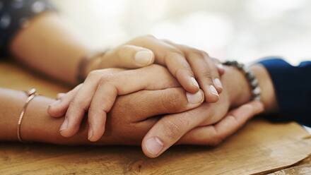 A close up shot of two hands holding onto one another