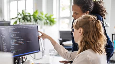 A woman points at a computer screen and gives advice on how to become a web developer.