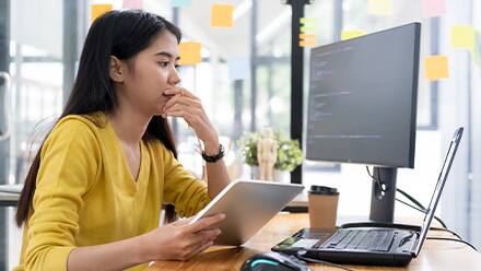 A woman looks at a computer screen studying how to become a software engineer