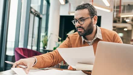 A professional considering master degree programs while sorting documents at a table