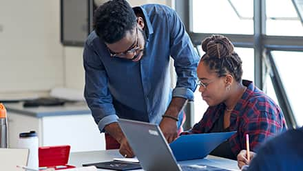 An instructor exhibiting qualities of a good teacher while helping a student review a document.