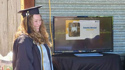 Samantha Sherwood '24, an SNHU graduate, in a cap and gown watching her name be called at SNHU's virtual Commencement.