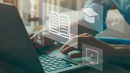 A person using a laptop to research what credit hours are with floating icons of a book, graduation cap, magnifying glass, person and trophy.