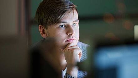 Programmer​ sitting at a desk looking at a computer screen