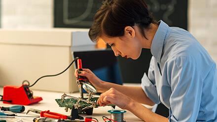 An electrical engineer using a soldering tool to build an electrical component