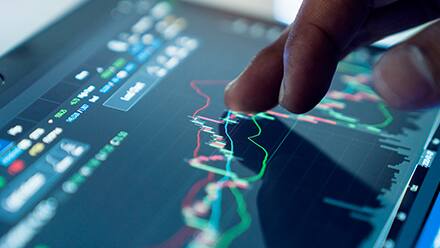 A hand hovering over a screen with a graph and different types of data on it showcasing what business analytics is