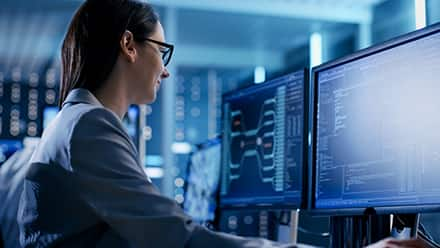 An information security professional working on a computer with two monitors.