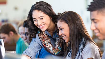 An educator earning her MEd and helping students working on computers.