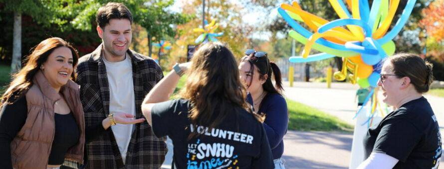 Five members of the SNHU community catching up at the Homecoming Street Fair