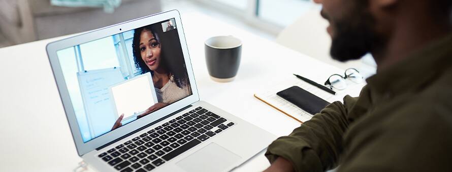 Two teammates collaborating on a school project through a video call made on a laptop.