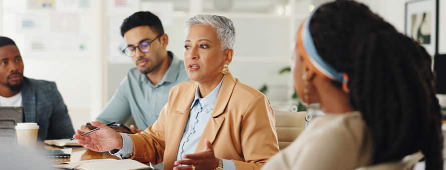 Four colleagues sitting at a meeting table, practicing conflict resolution skills.