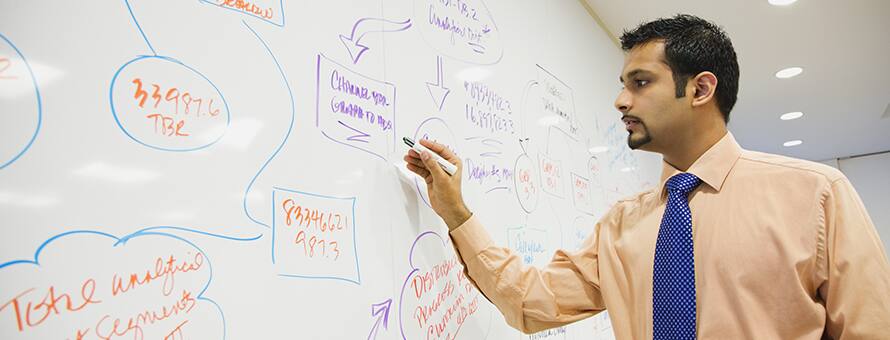 Man writing on white board putting his quantitative and qualitative data analysis skills into practice