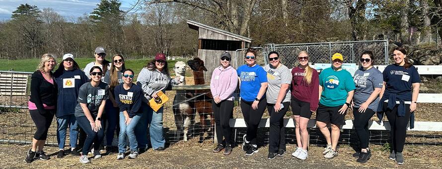 A group of 14 volunteers at 2 alpacas at the Joppa Hill Farm Spring Maintenance service project during Global Days of Service