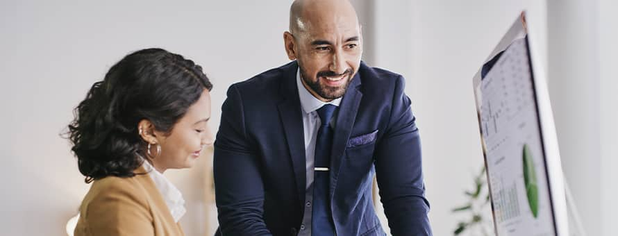 Two people in finance and accounting job roles, reviewing data on a computer.