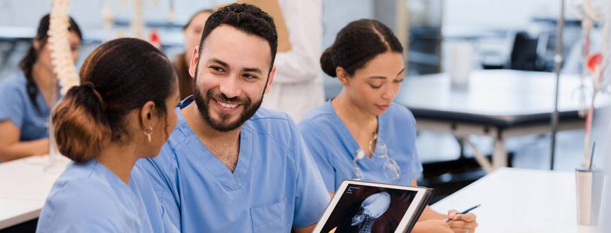 Three nurses in blue scrubs, working together in a professional development seminar