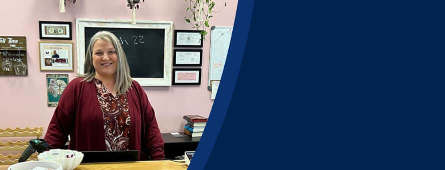 Heather Wejroch '23, an SNHU bachelor's in business administration graduate, standing behind the counter in Pages and Grapes.