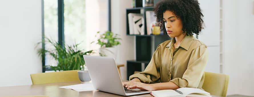 A student sitting at her laptop working on her college thesis paper.