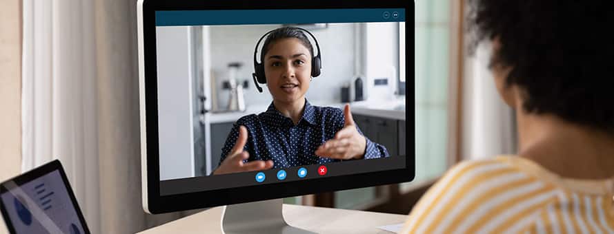 An academic advising sitting at their desktop in a video call with a student.