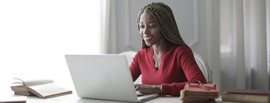 A student using a laptop to research how to write an MFA thesis