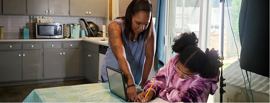 Latisha Aguilar '21, an SNHU graduate with a bachelor's in psychology, helping her daughter with homework at the kitchen table 