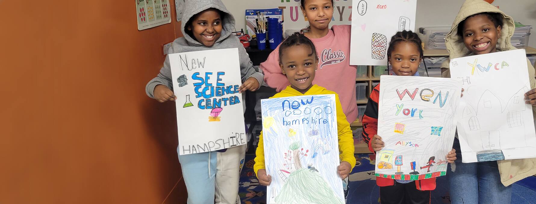 A group of children at the Center for New Americans holding up drawings