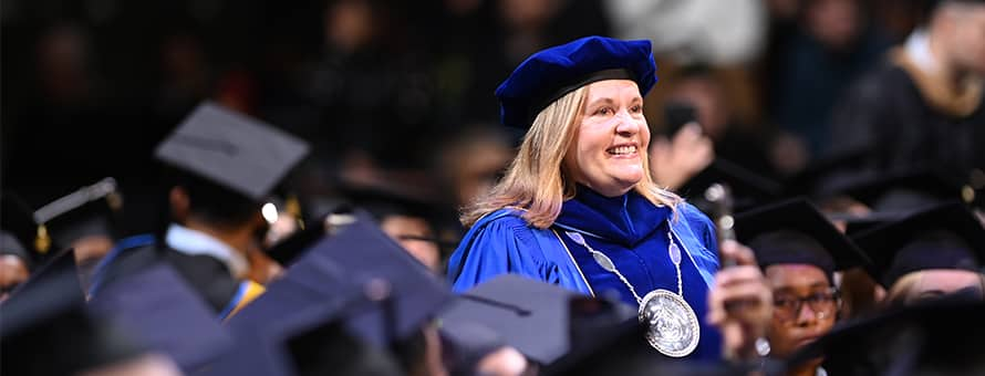 SNHU President Lisa Ryerson walking through a group of graduates for 2024