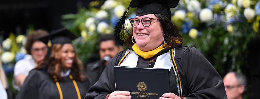 An SNHU graduate at Commencement earning their degree