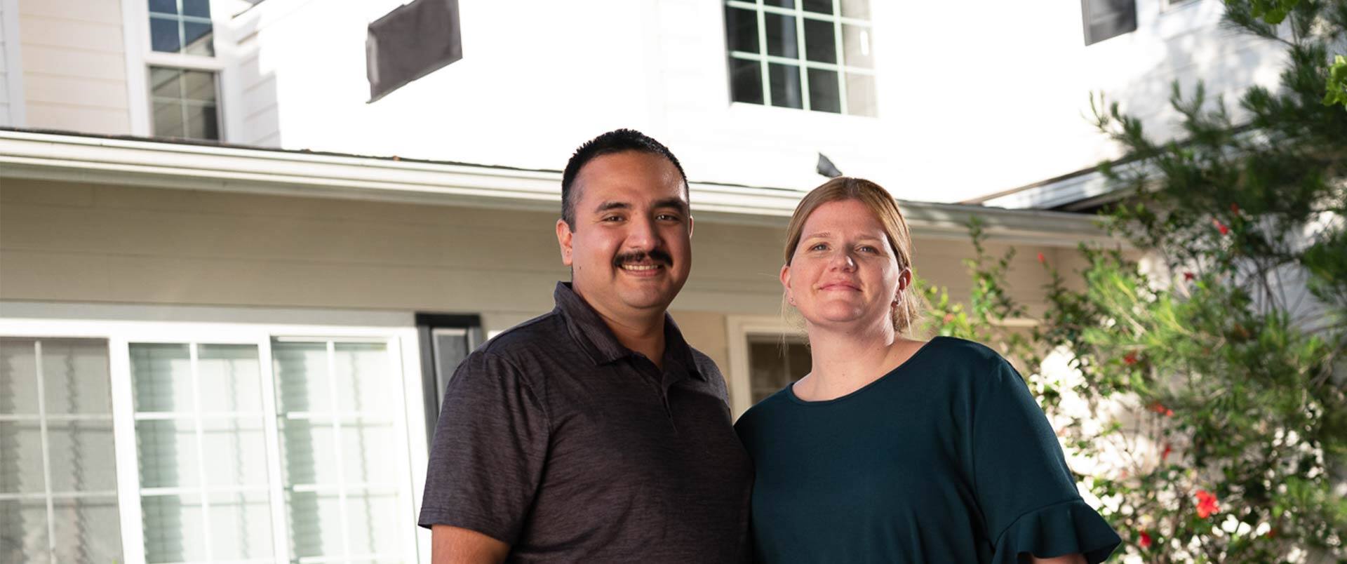 Shelly and Salvador Villa, two SNHU graduates, standing outside their home and smiling