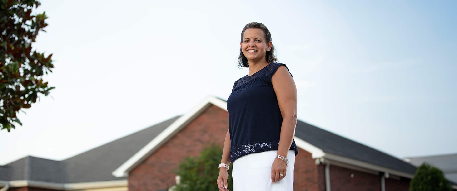 Kristi Galvin, who earned her online degree in human resources, standing in front of a house.