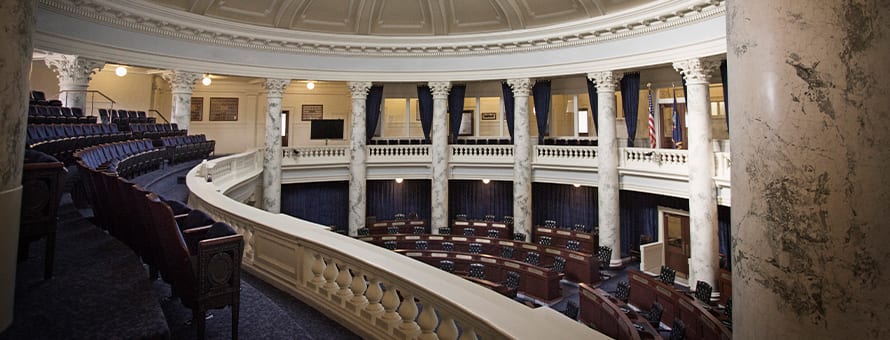 The interior of the U.S. Congress viewed from above showing dark brown wooden seats and marble columns.