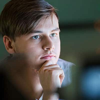 A computer programmer​ sitting at a desk looking at a computer screen