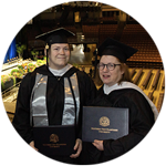 Delaware residents and SNHU graduates Jenny Gardner and Susan Lasala wearing their cap and gowns in the SNHU Arena for Commencement.