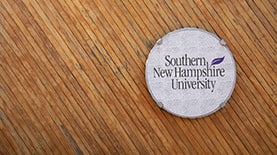 SNHU logos over a wood background