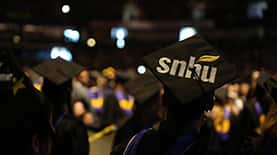 Student at Commencement with the SNHU logo printed on their cap. 