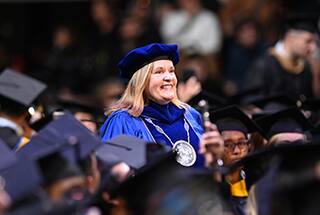 SNHU President Lisa Ryerson walking through a group of graduates for 2024