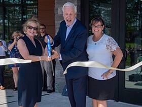 SNHU President Paul LeBlanc cutting a ribbon opening Kingston Hall with two women.